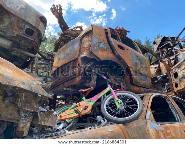 An old children\'s bicycle in a car\
graveyard. The consequences of the war in\
Ukraine.