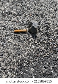 An Old Cigarette Bud And A Stone On A Rocky Ground