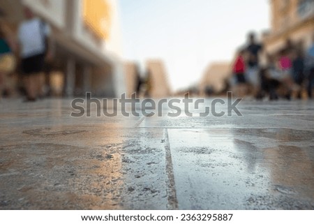 OLD CITY STREET WITH BLURRY PEOPLE WALKING IN THE CITYSCAPE CENTER, OUTDOOR DESIGN WITH EMTPY WET FLOOR