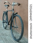 An old classic bike on a wall background. A round bicycle headlight in close-up. A stylish, fashionable bike. A black bicycle after restoration.