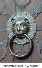 Old Classic Copper Doorknob In Shape Of Lion Head. With Ring Mounted On Dark Vintage Wooden Door, Close-up. Vertical