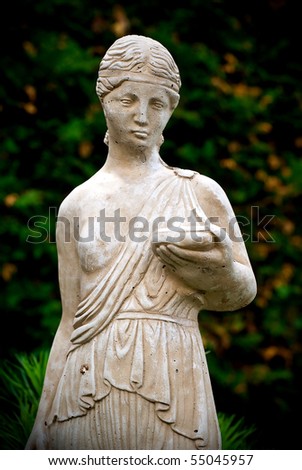 An old, classical style stone statue of a young woman holding a book.