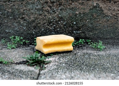 An Old Cleaning Sponge In Front Of An Old House Wall In The City