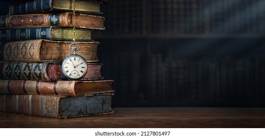 Old clock hanging on a chain on background of old books. Retro clock as a symbol of time a books are a symbol of knowledge. Concept on the theme of history, nostalgia, culture, vintage,  antique.  - Shutterstock ID 2127801497