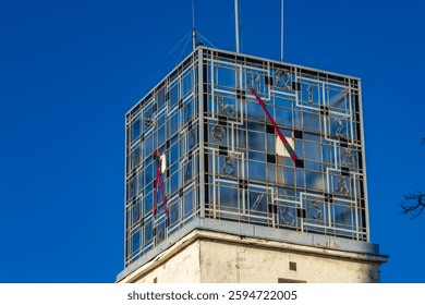 An old clock on a high tower against the blue sky, the clock face on the town hall tower