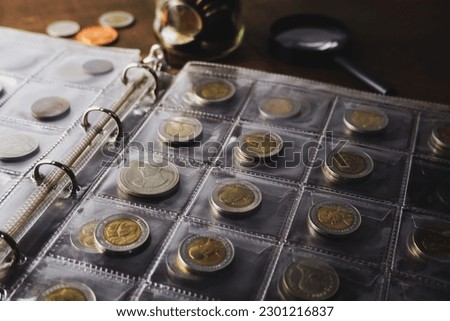 Old collectible coins on a wooden table. Dark background. Banner. Numismatics, Coins in the album. Magnifying glass, Selective focus.