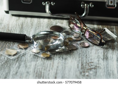 Old collector's coins, magnifying glass and glasses, soft focus background