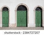 Old colonial facade with three green wooden doors.