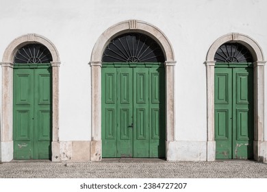 Old colonial facade with three green wooden doors.