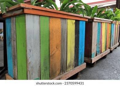 Old, colorful wooden pallets of the local 1165 x 1165 mm standard size to fit in the RACE container of the Australian railways made into decorative planter boxes, Queen Victoria Market. Melbourne-VIC.