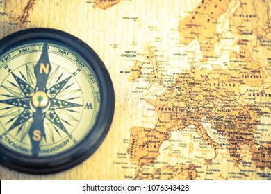 An Old Compass On Vintage World Map. Compass On Map Background. Close-up Of Ancient Boat Compass Aboard On Old World Map. Focus On Europe.