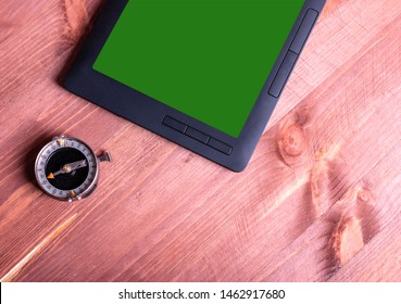Old compass, tablet with green screen on wooden background
