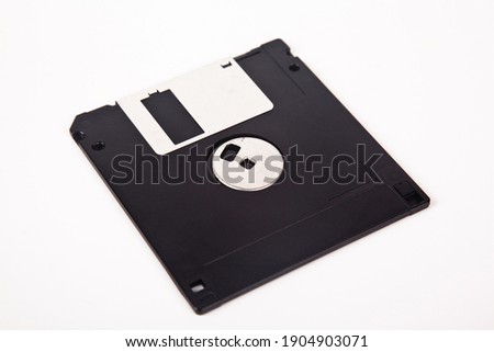 Old computer and data storage technology, black plastic magnetic floppy disk 3½ inches, isolated on white background