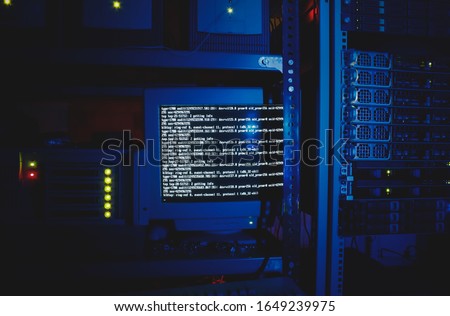 An old computer monitor in a dark blue server datacenter environment