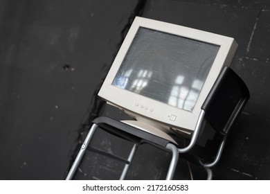 Old Computer Monitor On The Chair On The Black Wall Background.