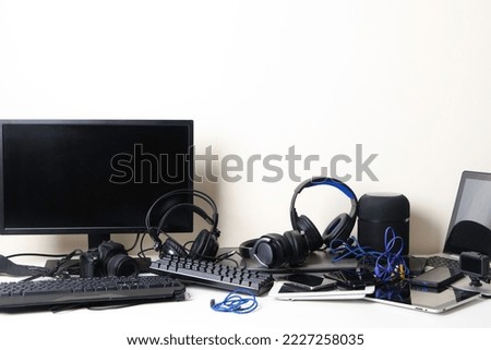 Old computers, digital tablets, mobile phones, headphones, many used electronic gadgets devices on white table. E-waste, planned obsolescence, electronic waste for reuse, refurbish and recycle concept
