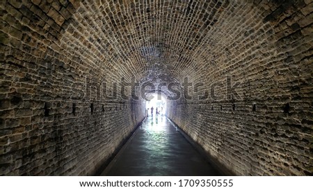 Old concrete and brick tunnel under ground in a picturesque location. Illuminated old train tunnel.