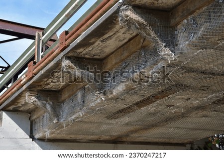 Old concrete bridge structure heavily damage. Dangerous overpass. Wire mesh retaining concrete structure falling apart. Erosion on concrete surface. Result of salt damage on bridge