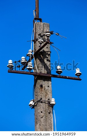 An old, concrete, unused electric pillarwith remains of porcelain insulators. Photo taken on a sunny day.