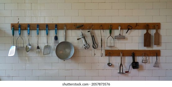 Old Cooking Utensils  Hanging On White Tiled Kitchen  Wall