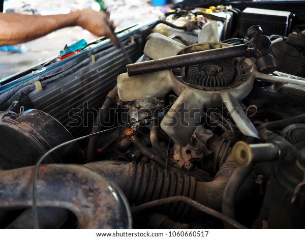 Old cooling fan motor of car is being removed in\
garage. Auto repair\
service.