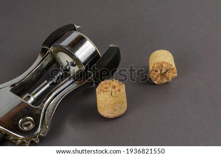 Old corkscrew and broken cork on a gray background. The corkscrew lies next to a broken wine cork. Selective focus