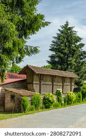 Old corn crib and brick structure standing along a quiet road in Molve, Croatia