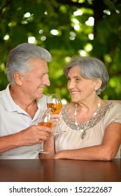 Old Couple Drinking Wine At The Table Outdoors