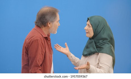 Old Couple Fighting And Shouting At Each Other During A Heated Argument. Old Couple Facing Conflicts While Living In A Relationship. Fighting Concept. Blue Background.S