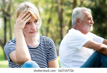 Old Couple Ignoring And Not Speaking Each Other Sitting On Grass In The Garden.Unhappy Old Couple.Angry Senior Couple Having An Argument In The Park.Marriage In Crisis.Relationship Problems.