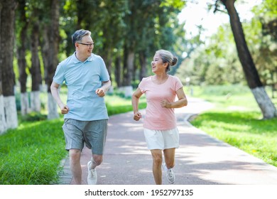 Old Couple Jogging In Outdoor Park Smiling