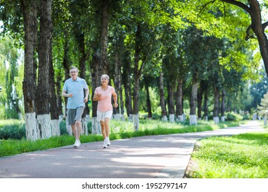 Old Couple Jogging In Outdoor Park Smiling