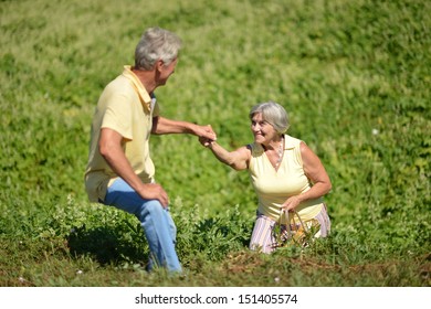 Old Couple In The Middle Of The Field With White Flowers