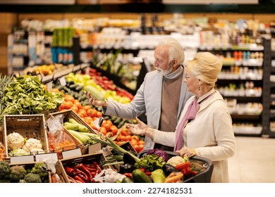 An old couple is picking fresh vegetables at the hypermarket. - Powered by Shutterstock