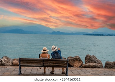 Old couple sitting on a bench on Lake Garda at sunset - Powered by Shutterstock