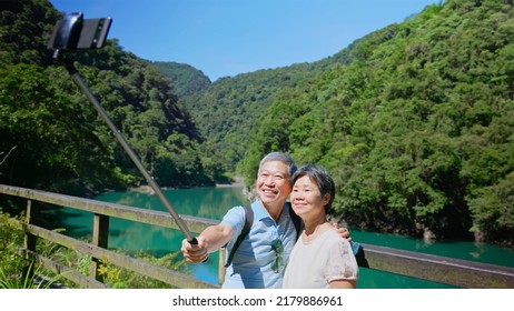 Old Couple Taking Selfie In Front Of The Lake And Mountain