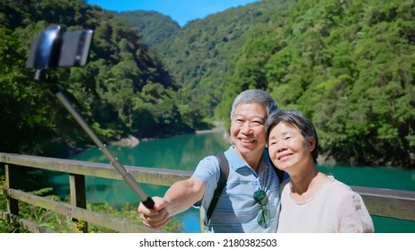 Old Couple Taking Selfie In Front Of The Lake And Mountain