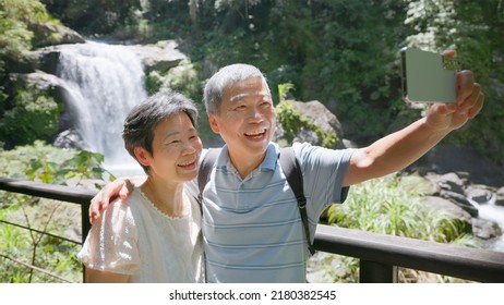 Old Couple Taking Selfie Video In Front Of The Waterfall