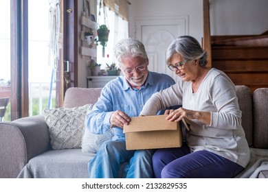 Old couple unpacking delivery box at home. Happy senior man and woman looking at carton box while sitting on sofa in living room. Elderly husband and wife checking out delivered stuff on couch - Powered by Shutterstock