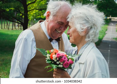 Old couple is walking in the green park. Grandmother and grandfather at golden wedding anniversary celebration. Grandma and grandpa laughing. Fifty years together romantic love story. Black and white.
