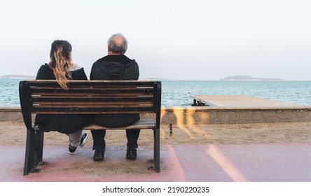 Old couple watching beautiful seascape, sitting on bench on shore. Good feelings, happy retirement lifestyle concept. Empty or blank copy space for advertising texts.