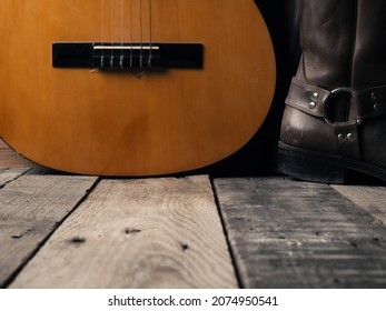 Old cowboy boots with an acoustic guitar on barn wood, space for your text