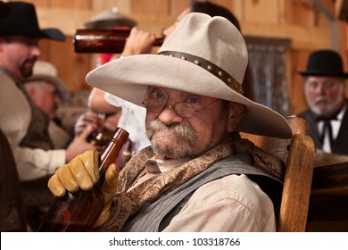 Old Cowboy Holding Whiskey Bottle In A Saloon