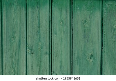 Old, cracked wood planks, painted a light green that had faded in the sun. Textured background.