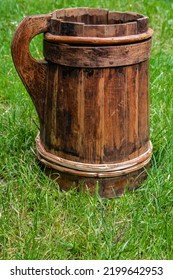 Old And Cracked Wooden Buckets Traditional Water Container .wooden Bucket Old And Weathered With A Handle Stands On The Grass Close-up