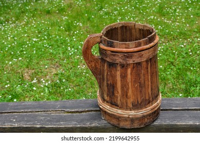 Old And Cracked Wooden Buckets Traditional Water Container .wooden Bucket Old And Weathered With A Handle Stands On The Grass Close-up