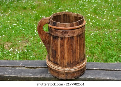 Old And Cracked Wooden Buckets Traditional Water Container .wooden Bucket Old And Weathered With A Handle Stands On The Grass Close-up