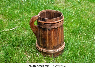 Old And Cracked Wooden Buckets Traditional Water Container .wooden Bucket Old And Weathered With A Handle Stands On The Grass Close-up