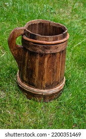 Old And Cracked Wooden Buckets Traditional Water Container .wooden Bucket Old And Weathered With A Handle Stands On The Grass Close-up