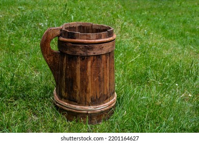 Old And Cracked Wooden Buckets Traditional Water Container .wooden Bucket Old And Weathered With A Handle Stands On The Grass Close-up